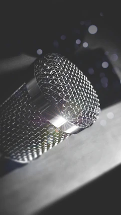 Close-up of a vintage microphone with silver tones reflecting soft studio lights.
