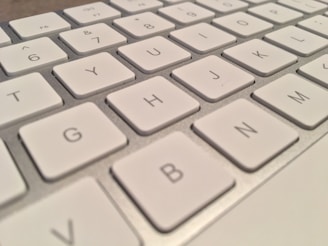 A close-up view of a white computer keyboard with visible keys such as G, H, J, and N. The keys are arranged in a standard QWERTY layout.