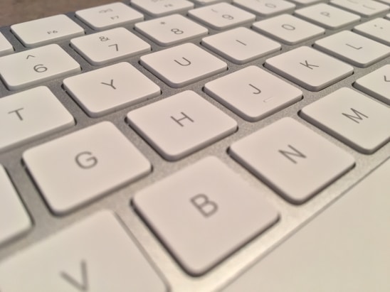 A close-up view of a white computer keyboard with visible keys such as G, H, J, and N. The keys are arranged in a standard QWERTY layout.