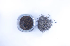Close-up of a glass jar filled with dried lavender and chamomile flowers on a wooden table.