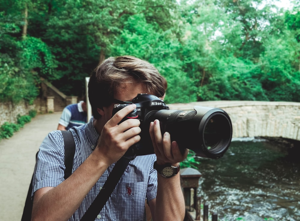 man taking photo using black Nikon DSLR camera