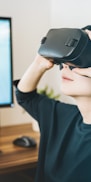 woman using black VR headset beside computer