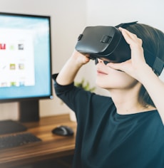 woman using black VR headset beside computer