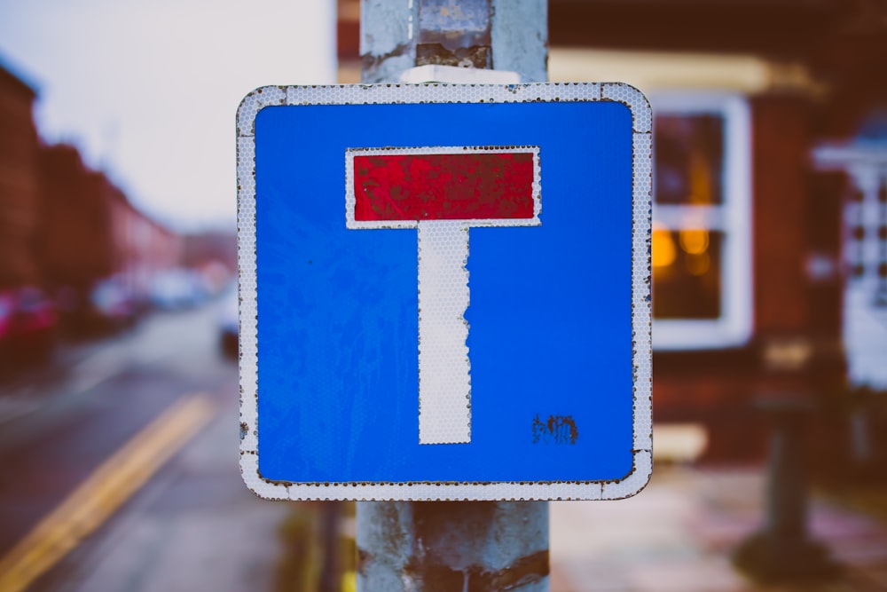 Weißes, blaues und rotes Straßenschild in der Nähe der Straße