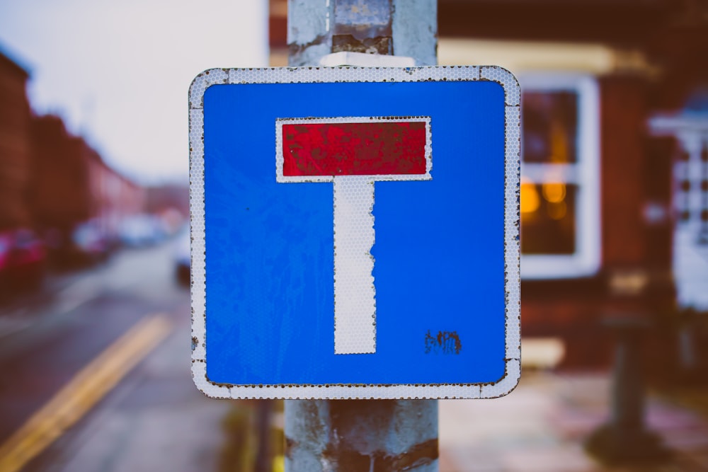 Cartello stradale bianco, blu e rosso vicino alla strada