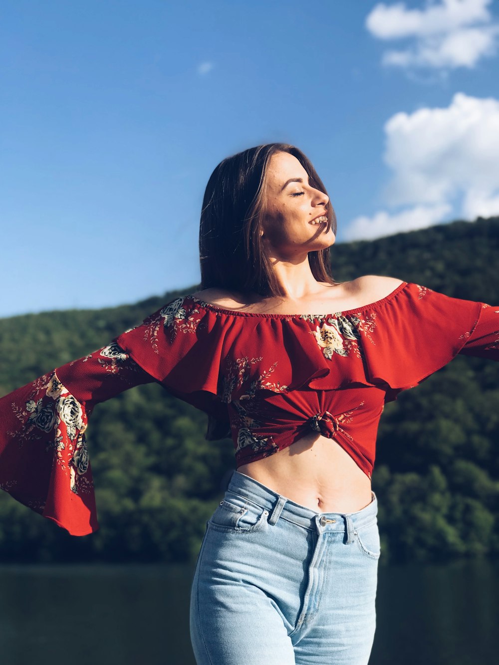 woman standing near body of water while closing her eyes