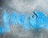 A concrete surface with a blue-colored water valve cover is partially surrounded by faint blue graffiti. The word 'WATER' is embossed on the circular cover, which is weathered with marks and scratches.