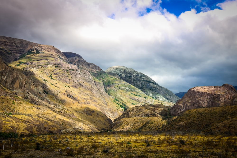 brown and green mountain under white clouds at daytime