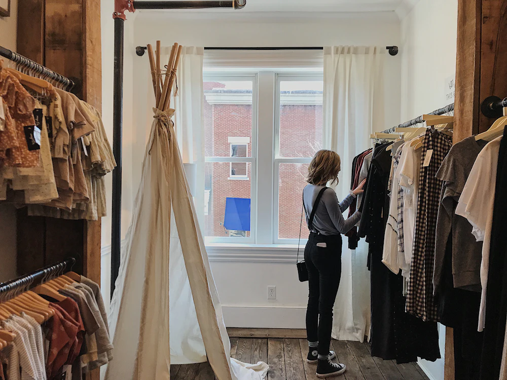 A woman looking through garments hanging on a rail inside a boutique