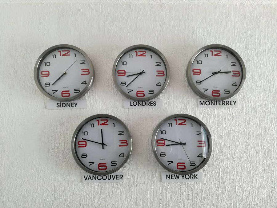 Cinq horloges murales de styles différents accrochées côte à côte sur un mur