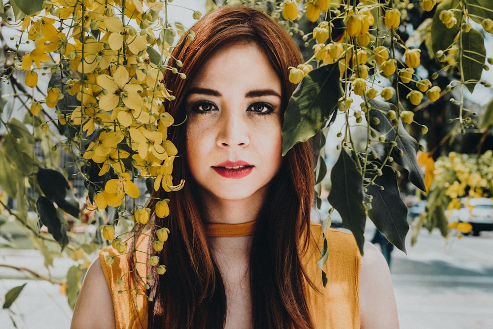 mulher posando para foto entre a flor amarela durante o dia