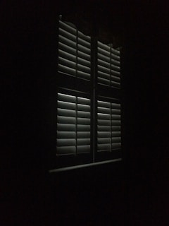 Bedroom window dressed with blackout curtains blocking all outside light for complete darkness.