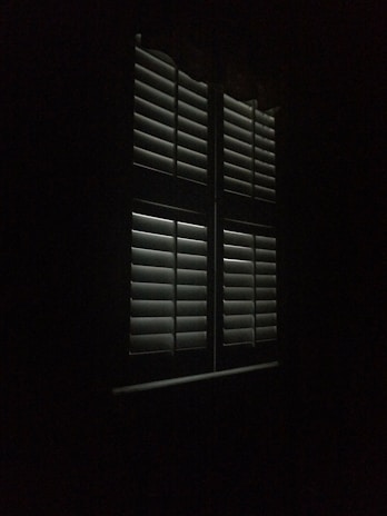 Bedroom window dressed with blackout curtains blocking all outside light for complete darkness.