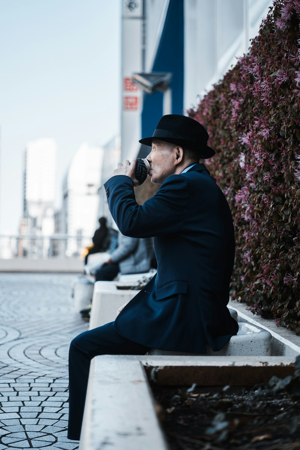 man sitting on chair beside floral wall