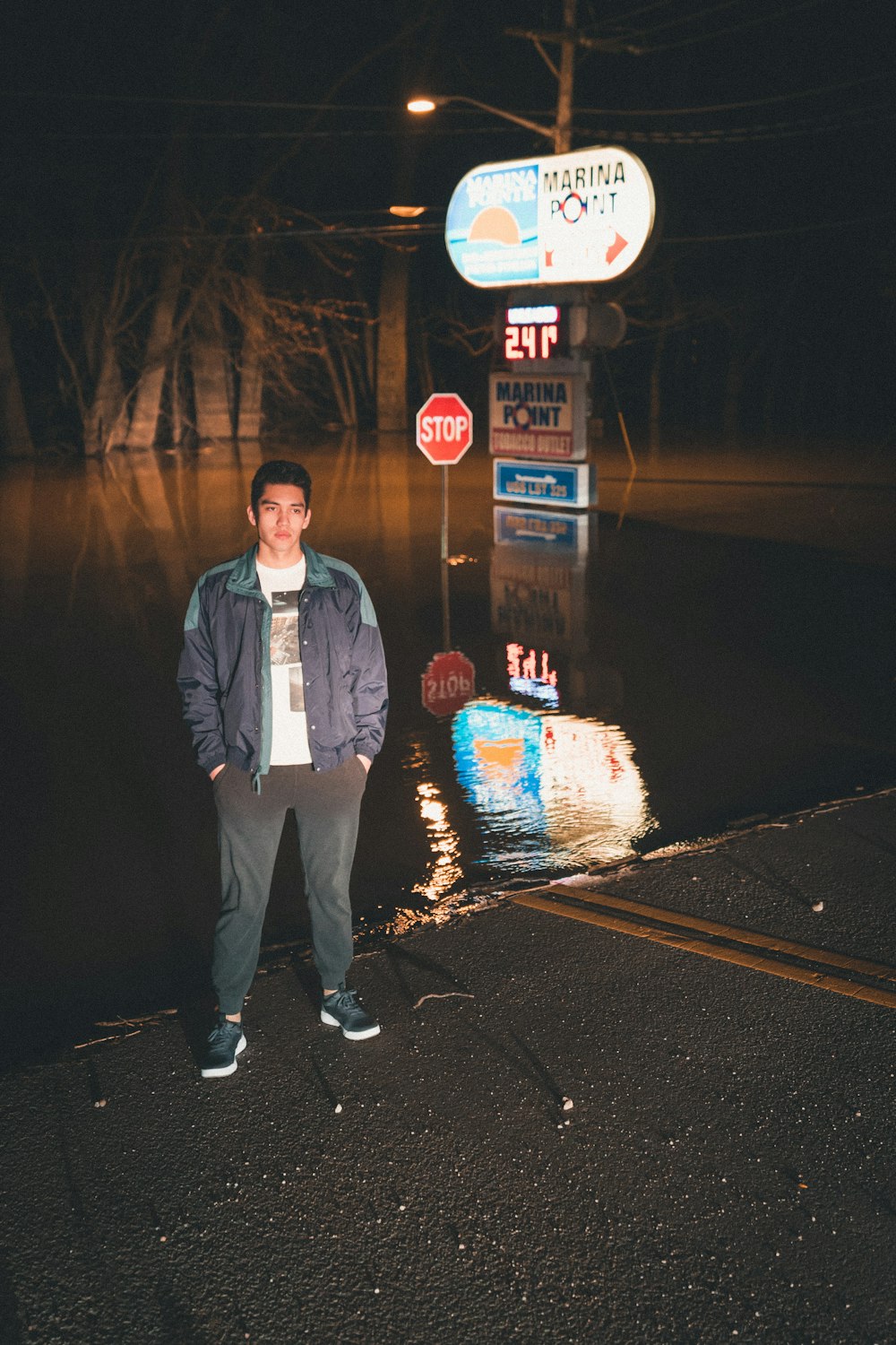 Hombre con chaqueta azul abotonada de pie cerca de la señalización de parada de inundación