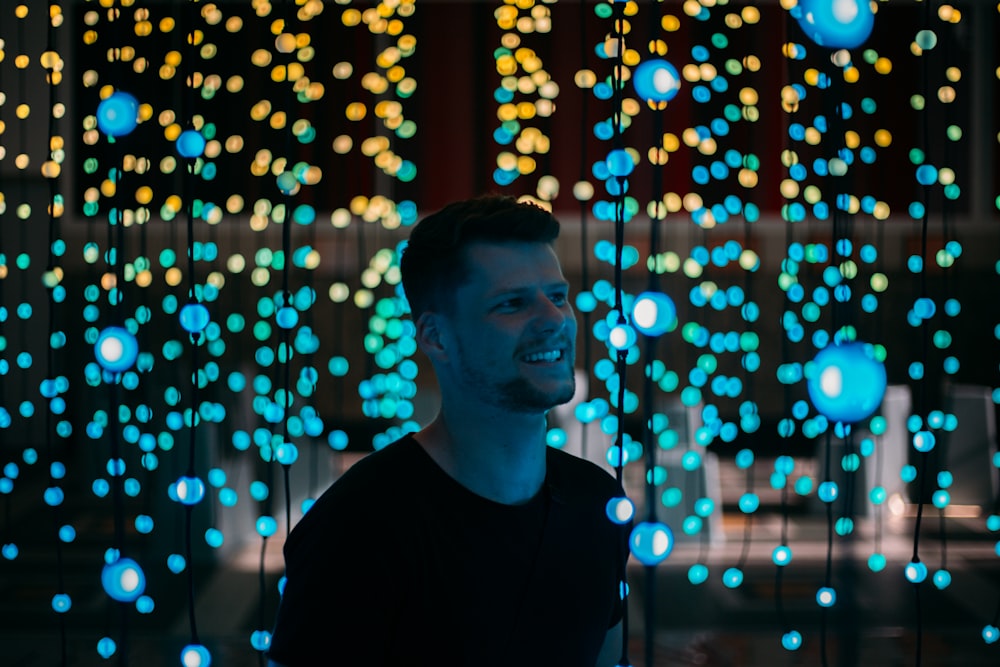 man standing between lighted drop string lights