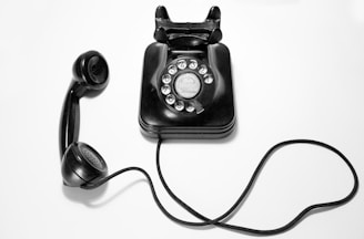 black rotary dial phone on white surface