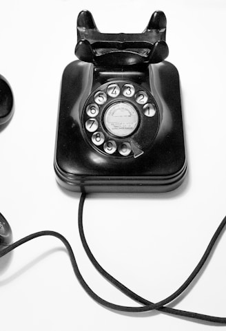 black rotary dial phone on white surface