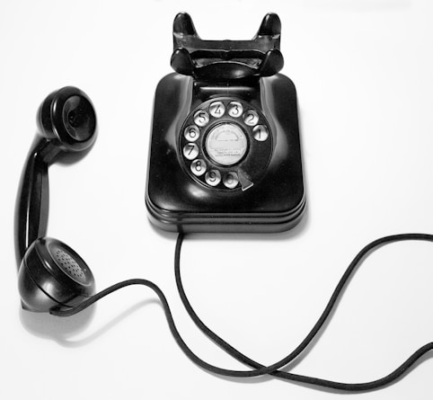 black rotary dial phone on white surface