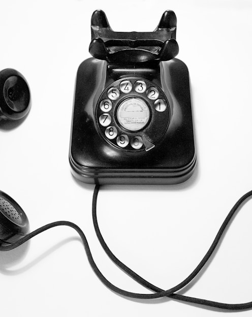 black rotary dial phone on white surface