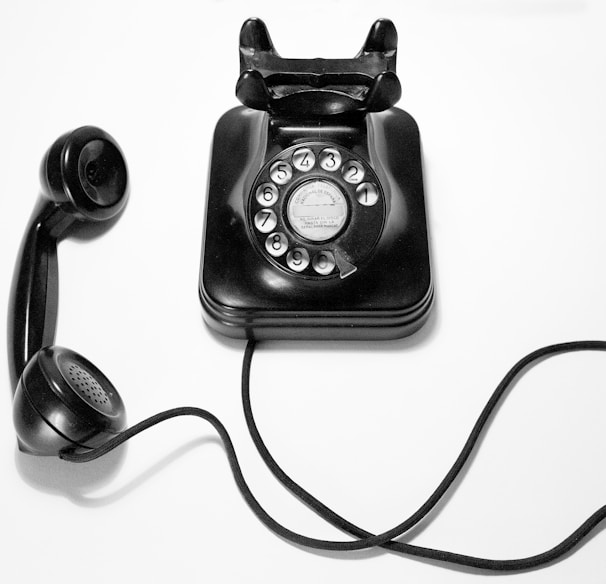 black rotary dial phone on white surface