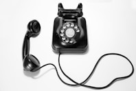 black rotary dial phone on white surface