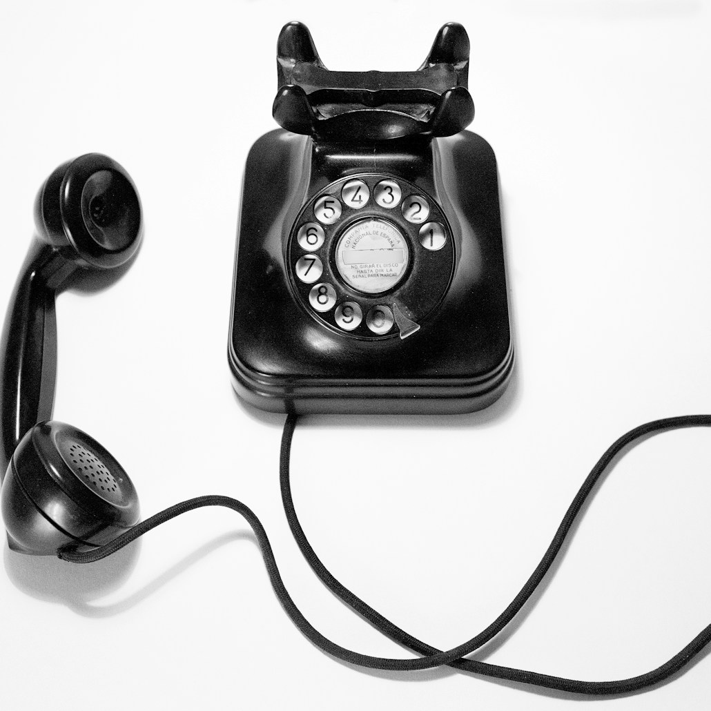 black rotary dial phone on white surface