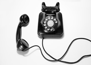 black rotary dial phone on white surface