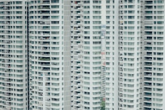 Tall residential buildings with numerous balconies and windows stacked vertically. The structure is repetitive, with each floor mirroring the one below and above, creating a uniform pattern.