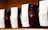 Several jars of rhubarb raspberry vanilla bean jam lined up on a shelf, each adorned with a white label. The jars are tightly sealed with black lids, and the contents appear to be thick and rich in texture, with visible seeds suggesting a homemade quality.