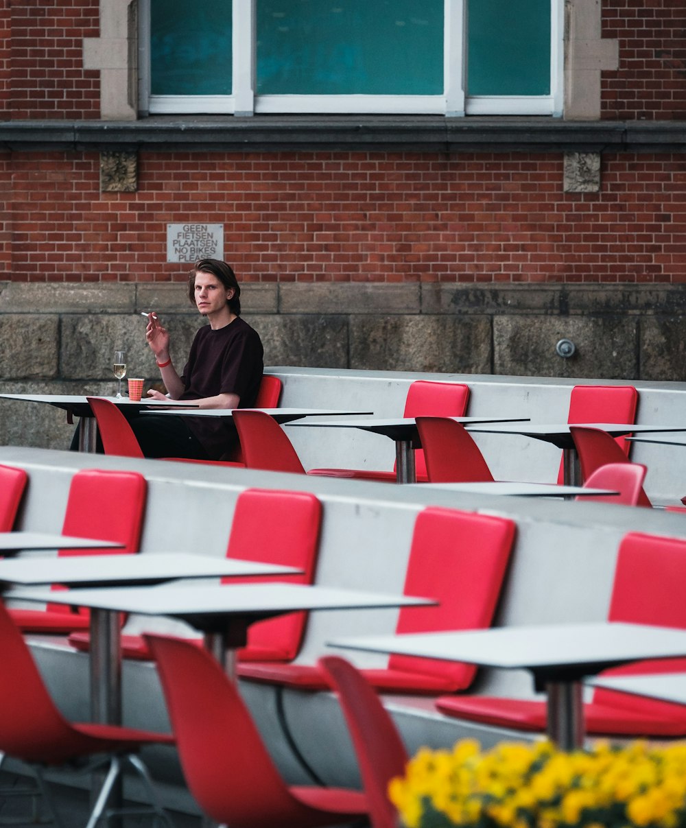 homme fumant une cigarette assis sur une chaise rouge