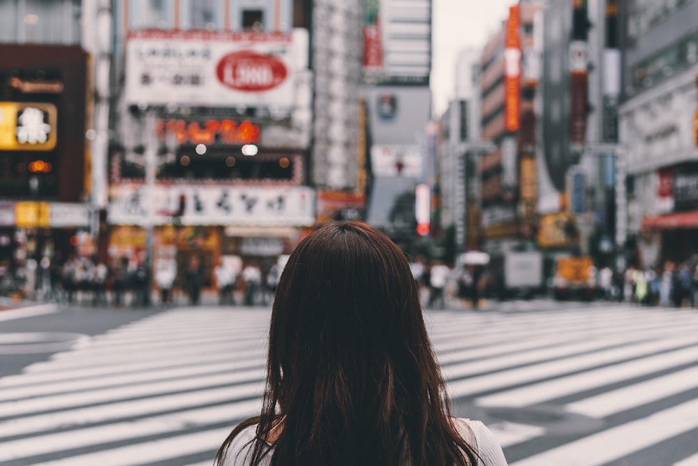 selective focus photography of woman standing on pedestrian lane