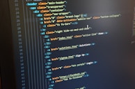 A computer monitor displays HTML code in an integrated development environment. The screen shows a structured hierarchy of HTML tags, including elements such as header, nav, and list items with classes and hyperlinks.