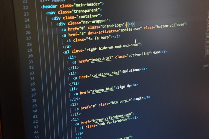 A computer monitor displays HTML code in an integrated development environment. The screen shows a structured hierarchy of HTML tags, including elements such as header, nav, and list items with classes and hyperlinks.