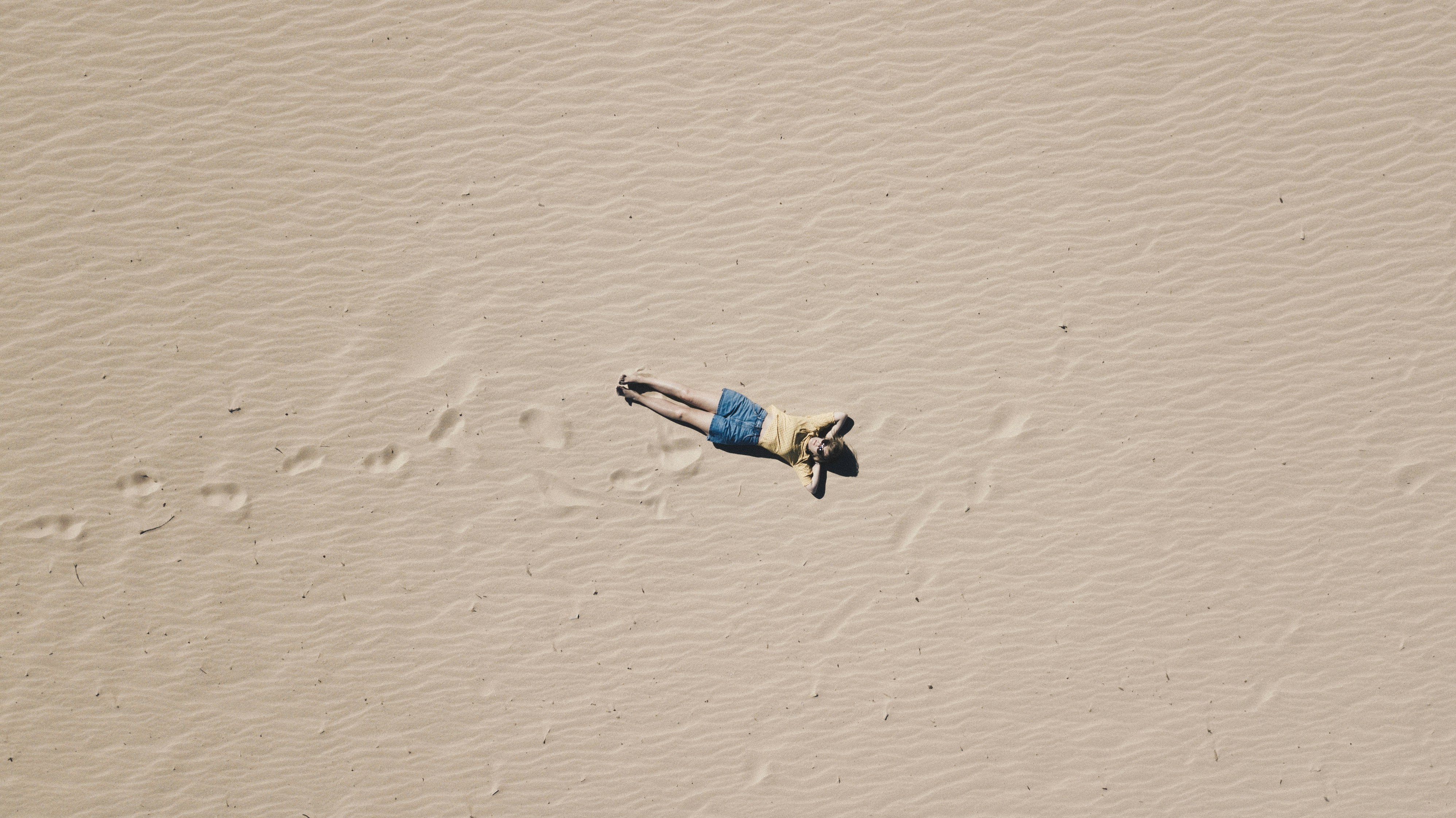 aerial photograph of man lying on sand