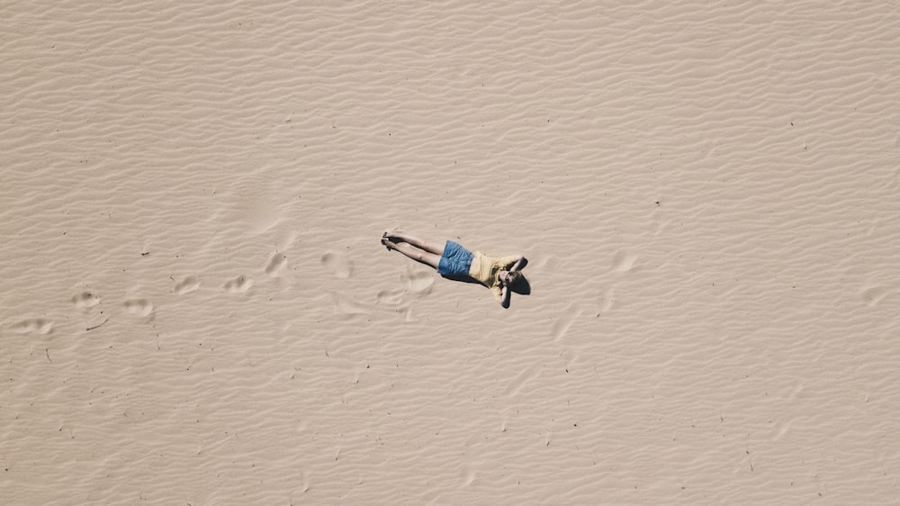 aerial photograph of man lying on sand