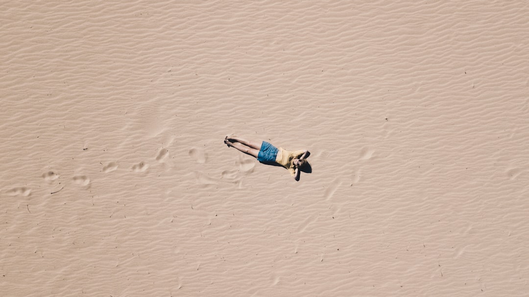 aerial photograph of man lying on sand