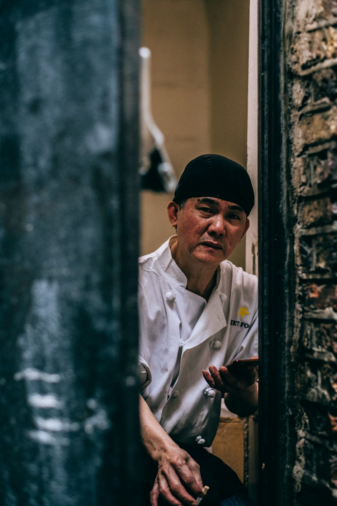 chef holding phone leaning on wall