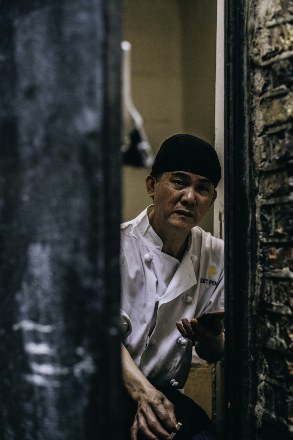 chef holding phone leaning on wall