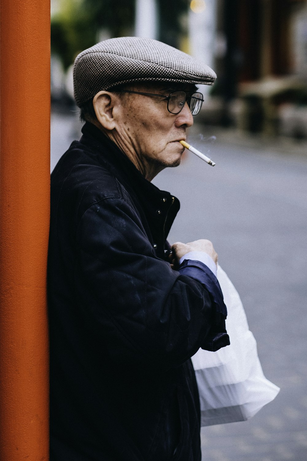 man standing beside post holding plastic bag