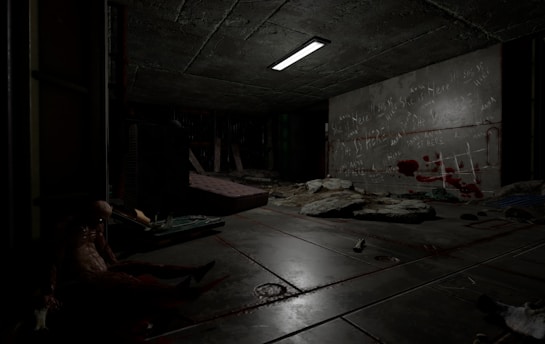 A dimly lit, sinister room with a concrete ceiling and floor, featuring scattered debris and a mattress. Graffiti and red marks resembling bloodstains cover one wall. A humanoid figure slumps against a wall, adding to the eerie atmosphere, while a flickering overhead light casts shadows.