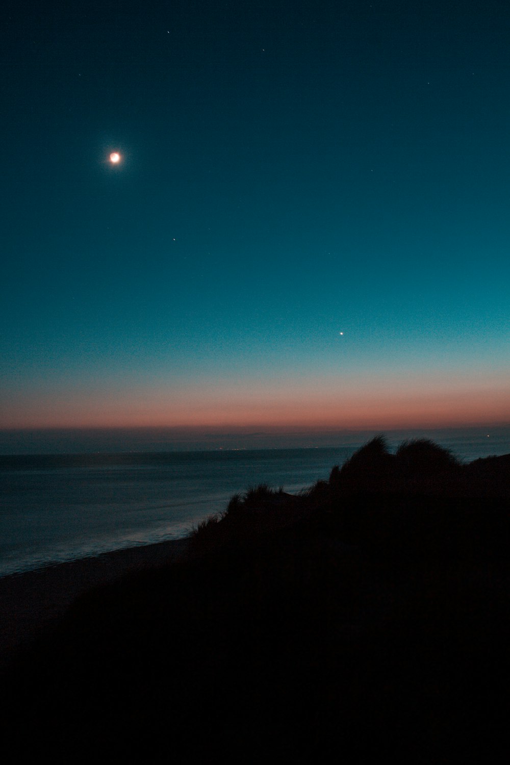 landscape photography of seashore against blue and orange skies