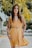 woman wearing orange sleeveless dress standing near yellow flower tree