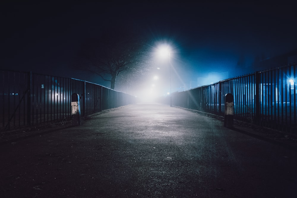 black concrete road beside metal fence