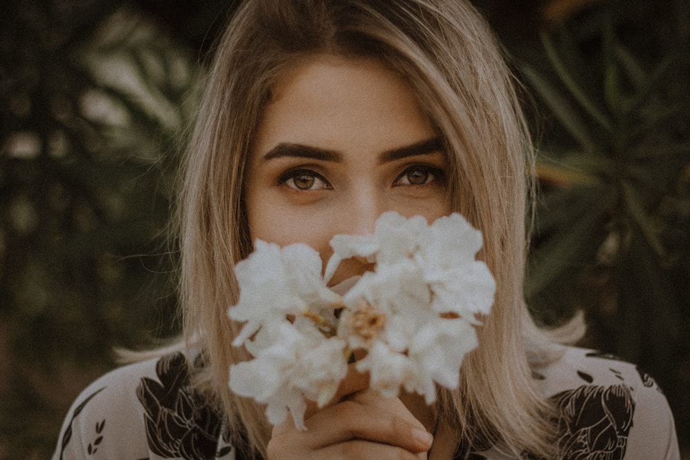 femme tenant une fleur à pétales blancs