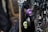 Various pendants and charms hang on black cords, including skull-shaped and ornate metallic designs. The focus is on a purple skull pendant, surrounded by intricate metallic figures and shapes.