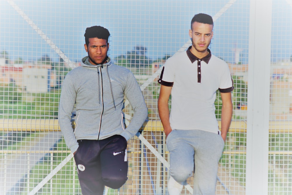 two men standing in front of fence