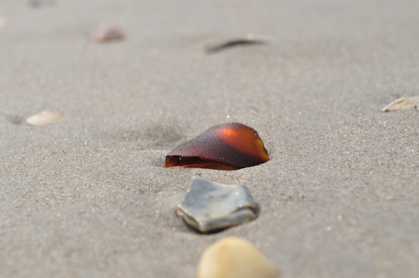 Close-up of vibrant cobalt blue sea glass pieces resting on black volcanic sand.