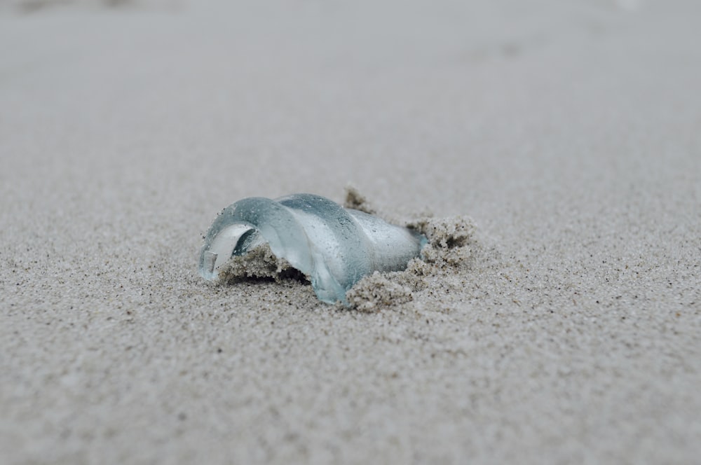 a piece of glass sitting on top of a sandy beach