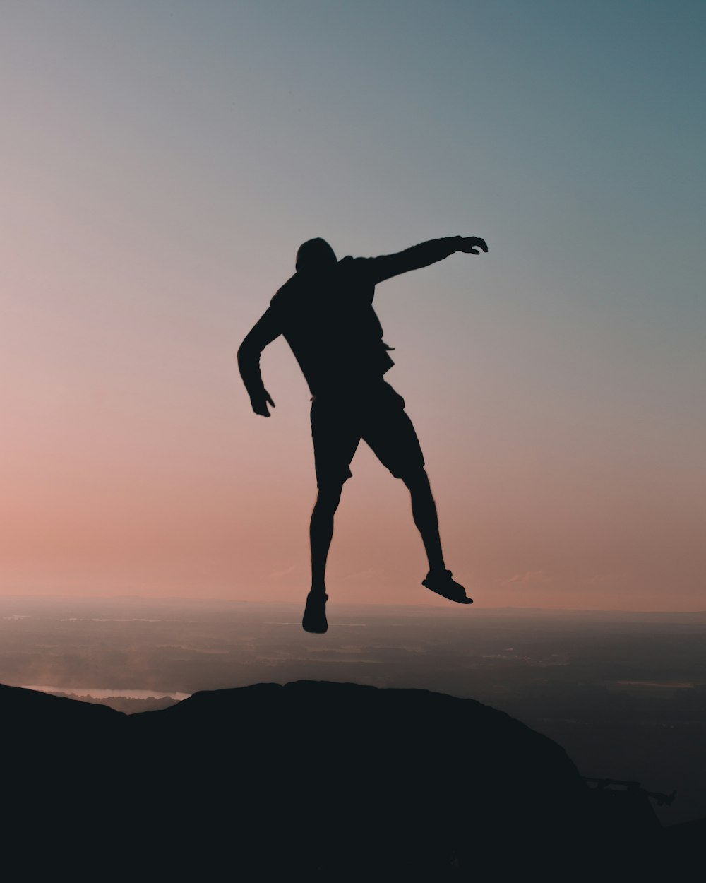 silhouette of man jumping on cliff at golden hour
